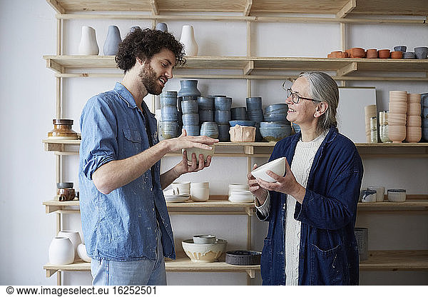 Man and woman discussing over bowl in pottery class