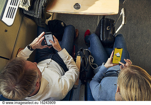 Man and woman in train using cell phones