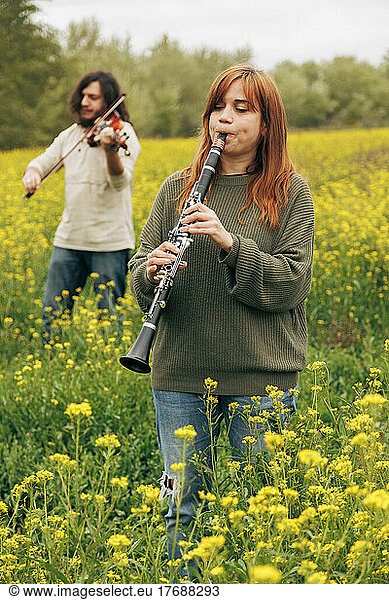 Man and woman practicing musical instruments in flower field