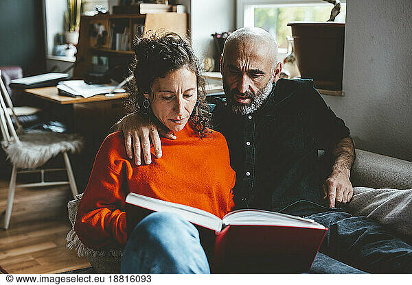 Man and woman reading book sitting at home