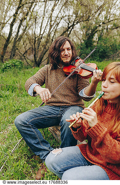 Man and woman rehearsing with musical instruments in field