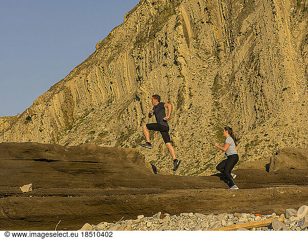Man and woman running on single trail on cliff of Getxo