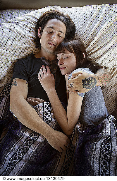 Man and woman sleeping on bed in camper van