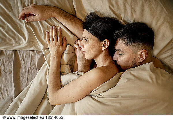 Man and woman snuggling in bed at home