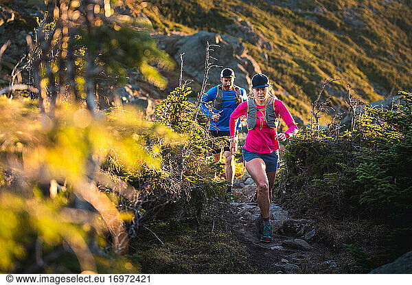 Man and woman trail running at sunrise in the mountains