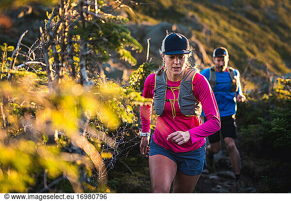Man and woman trail running at sunrise in the mountains
