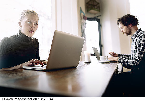 Man and woman using laptop in cafe