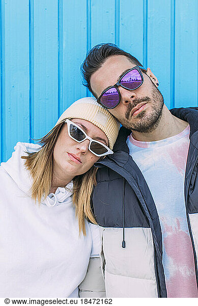Man and woman wearing sunglasses in front of wall