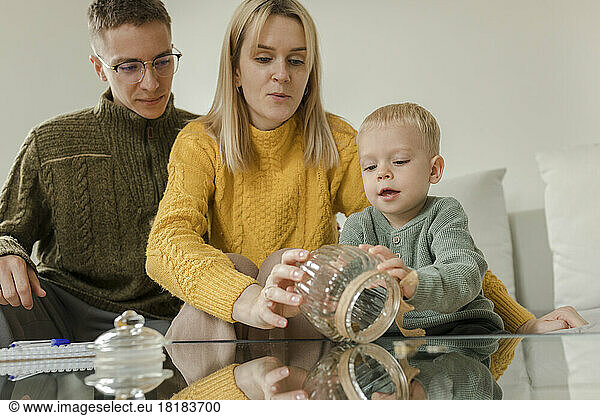 Man and woman with son holding jar in living room at home