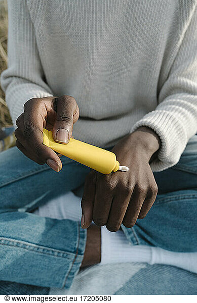 Man applying cream on hand through tube