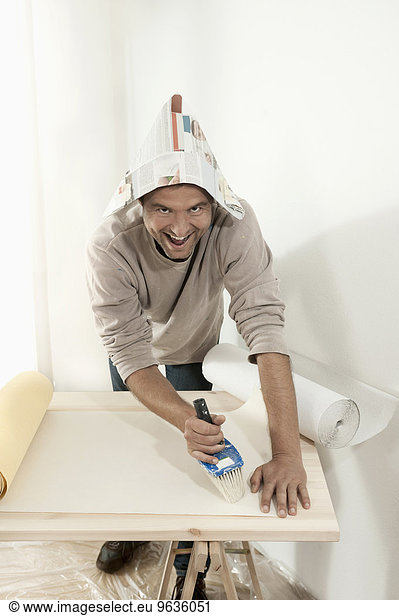 Man applying glue on wallpaper with a brush