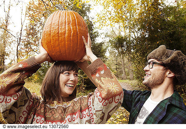 Man assisting woman in carrying Halloween pumpkin