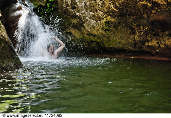 Man bathing under waterfall