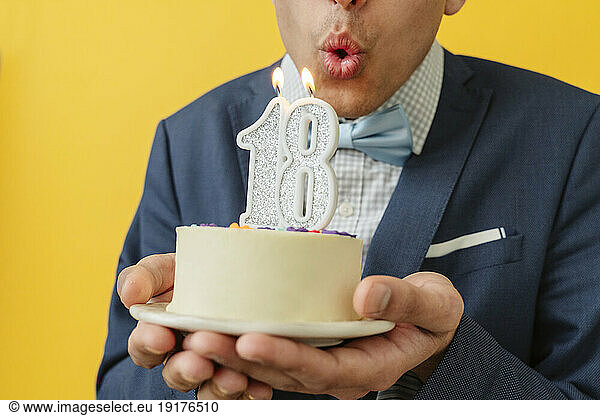 Man blowing 18th birthday candle on cake