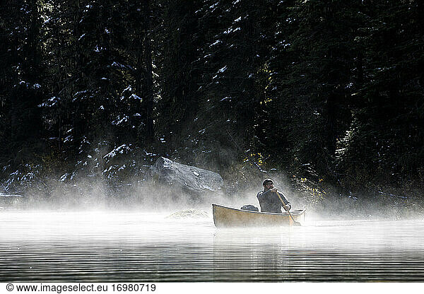 Man boating on a secluded lake on a foggy autumn day