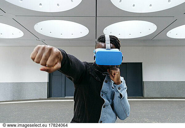 Man boxing wearing virtual reality headset under illuminated ceiling