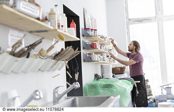 Man browsing art supplies on shelf in pottery studio