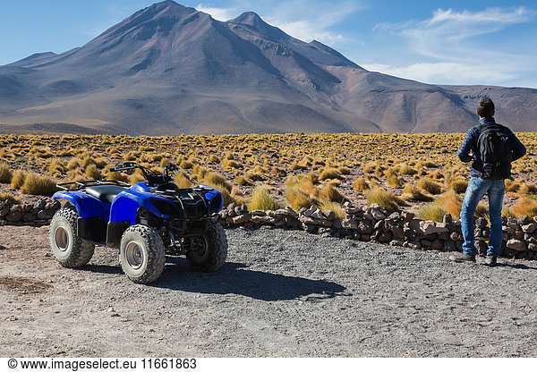 Man by quad bike looking at mountain  San Pedro de Atacama  Chile