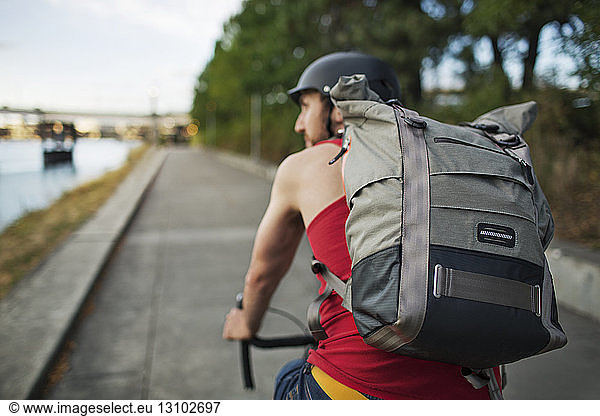 Man carrying backpack while riding bicycle on street