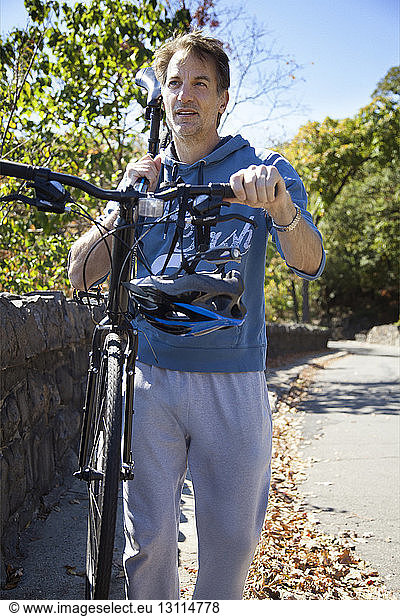 Man carrying bicycle on shoulder while walking on road