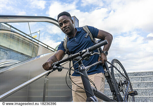 Man carrying bicycle on staircase