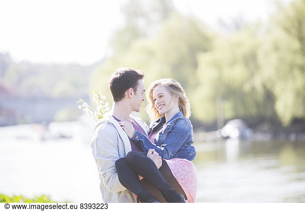 Man carrying girlfriend along river