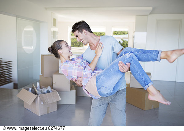 Man carrying girlfriend in new house