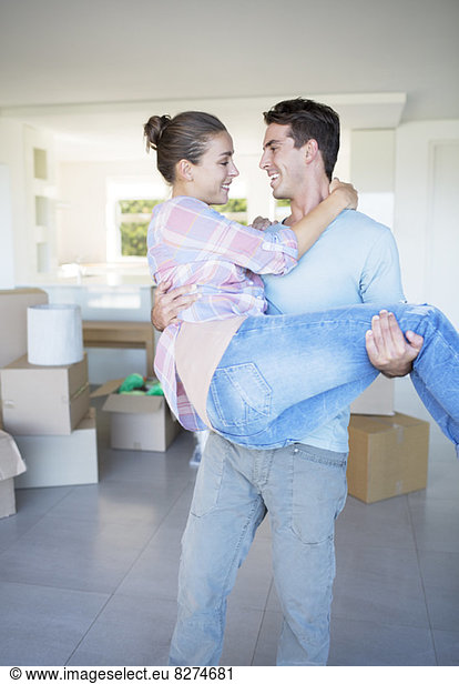 Man carrying girlfriend in new house
