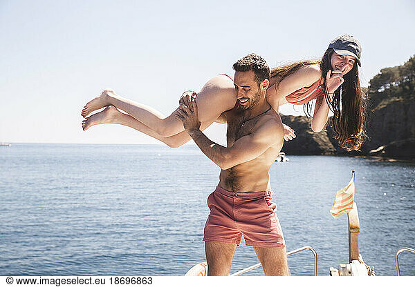 Man carrying girlfriend on yacht at sunny day