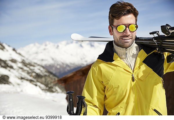Man carrying skis on mountain top