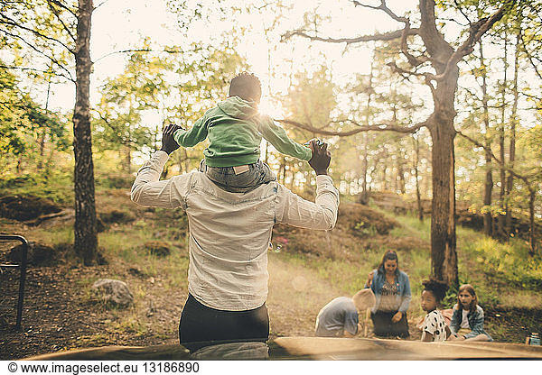 Man carrying son shoulders during picnic with family in public park