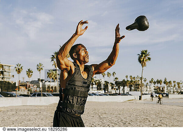 Man catching and exercising with kettlebell on beach