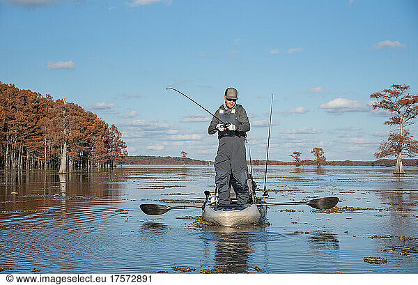 man catching bass out of kayak