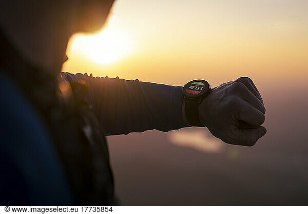 Man checking smart watch at sunset