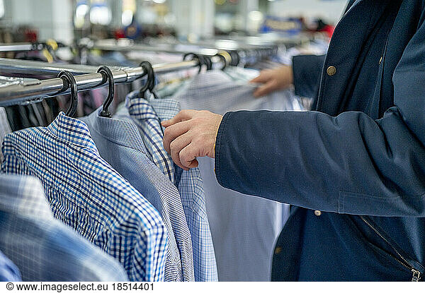 Man choosing clothes from rack in store
