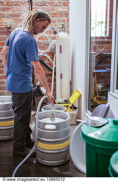 Man cleaning beer kegs in microbrewery