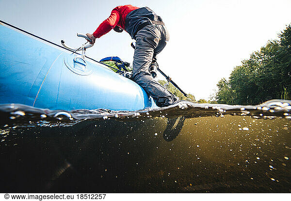 Man climbing out of water onto drift boat