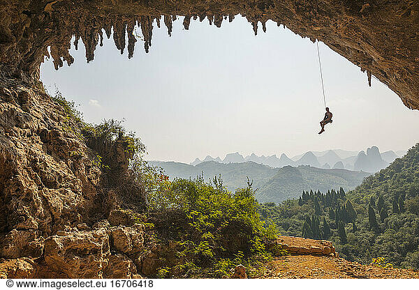 Man climbing the arch at Odin's Den next to Moon hill in Yangshuo