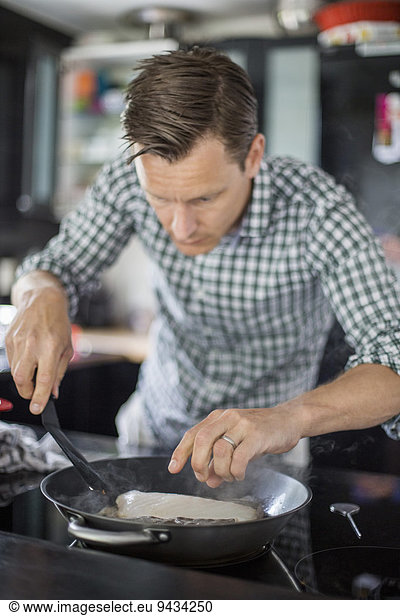 Man cooking fish in kitchen