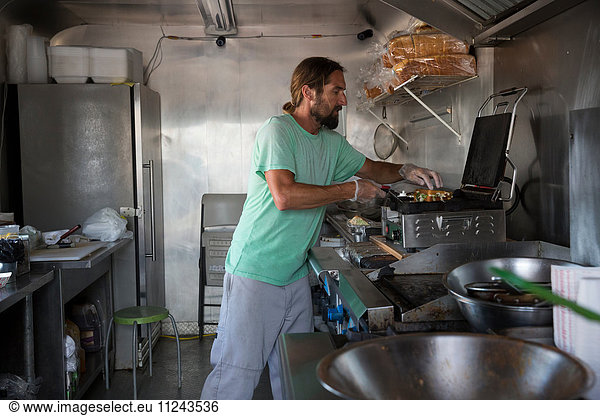 Man cooking food in fast food trailer