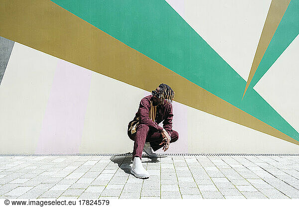 Man crouching in front of colorful wall