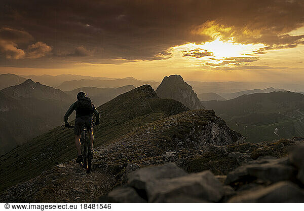 Man cycling on mountain at sunset
