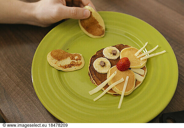 Man decorating pancakes in shape of bunny at home