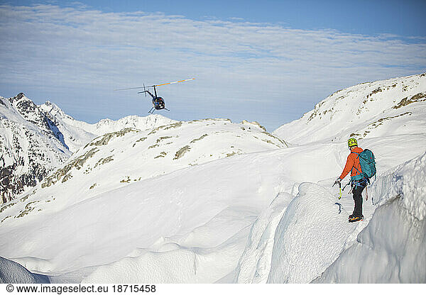 Man directing helicopter on snow-covered mountain