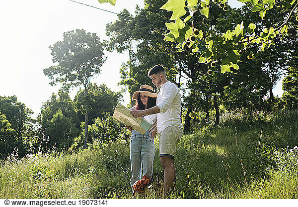 Man discussing over map with girlfriend standing on grass at park