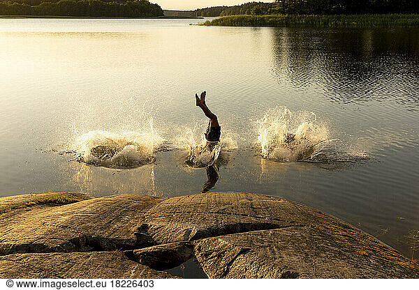 Man diving and splashing water in lake at sunset