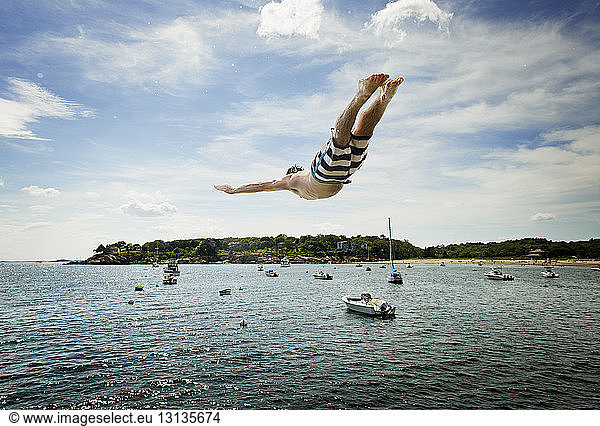 Man diving into sea against sky
