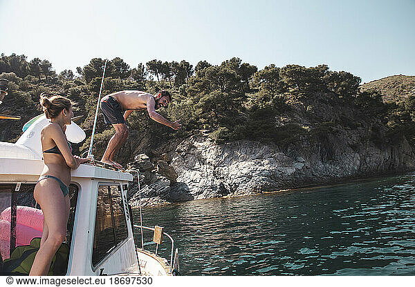 Man diving into water standing on yacht at vacation