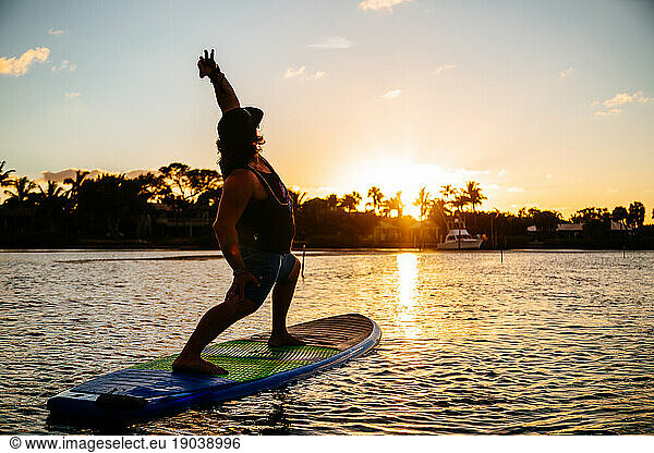 Man does sunset yoga on his paddle board