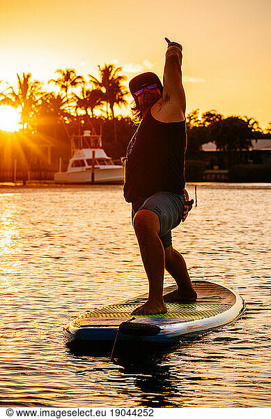 Man doing yoga on his standup paddle board